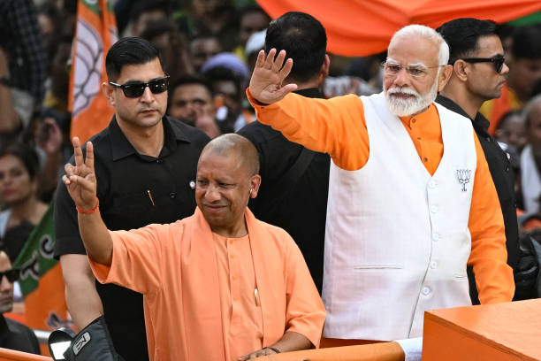 Narendra Modi (2R), India's Prime Minister and leader of the ruling Bharatiya Janata Party (BJP) with Yogi Adityanath (2L), Chief Minister of the country's Uttar Pradesh state waves to the crowd during a roadshow on the eve of filing of his election nomination papers, in Varanasi on May 13, 2024. Tens of thousands of supporters gathered on May 13, to catch a glimpse of Narendra Modi in the holy city of Varanasi as the Indian Prime Minister stepped up campaigning in the country's marathon election. (Photo by Sajjad HUSSAIN / AFP) (Photo by SAJJAD HUSSAIN/AFP via Getty Images)